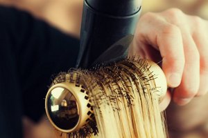 Blonde hair being dried and curled around a rounded brush